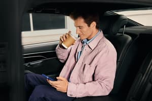  Man drinking a hot drink in the back seat of a vehicle