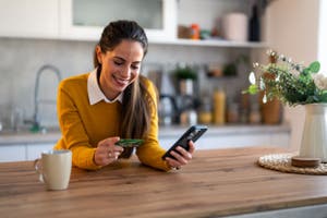 A woman smiling while looking at her card and mobile phone