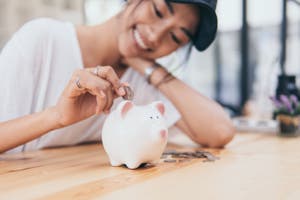 Image of a women putting money in a money box.