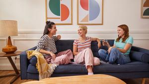 Three women on a couch talking and laughing.