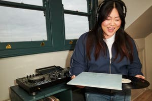 A person pulling a vinyl record out of a sleeve after using a buy now, pay later service to purchase a record player in store.     