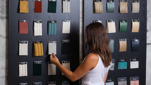 Customer browsing wallpaper samples in The Wallpaper Company showroom beneath a #DressYourWall sign