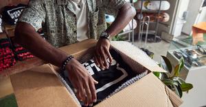 Man placing shirts in a cardboard box, preparing to ship to customers