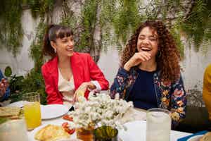 Zwei Frauen sitzen in einem Restaurant und lachen.
