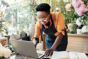 Eine Person nutzt in einem Blumenladen einen Laptop, um auf ein Online-Banking-Portal zuzugreifen.