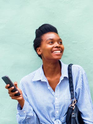 Frau steht draußen in der Sonne und hält ihr Handy