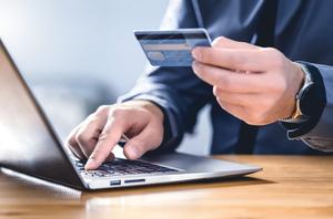 A man enters payment cards details online using a laptop.