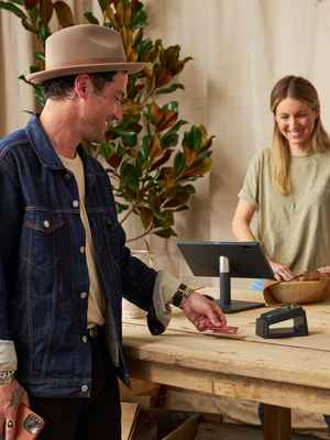 A happy man paying with a PayPal Zettle card reader at a store