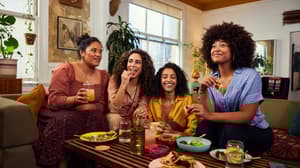 4 friends talking happily over a meal, showing an example of people who trust PayPal to send, spend, and manage their money