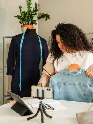 A fashion designer using PayPal business solutions on her mobile phone and tablet to streamline operations