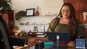 A smiling business owner using her PayPal Zettle-integrated POS system to help a customer check out