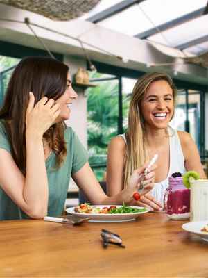 3 friends talking happily over a meal, showing an example of people who trust PayPal to send, spend, and manage their money