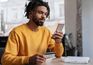 Man holding credit card, using smartphone for online shopping