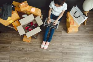 Female business owner preparing shipping of clothing items at home