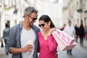 Couple walking down the street holding shopping bags and smiling