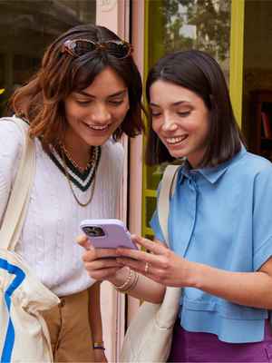 Due amici sorridenti in un negozio che indicano i telefoni: esempio di circostanza in cui è possibile inviare denaro con PayPal.