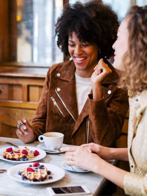 3 amis discutant joyeusement autour d'un repas, comme un exemple de personnes qui font confiance à PayPal pour envoyer, dépenser et gérer leur argent