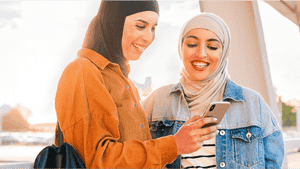 Zwei Frauen schauen auf ein Telefon und lächeln