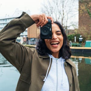 Smartphone-Display mit dem Bild einer Person, die vor einem fast vollständig blauen Himmel lächelt.