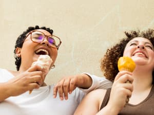 Zwei Frauen lachen und essen Eiscreme.
