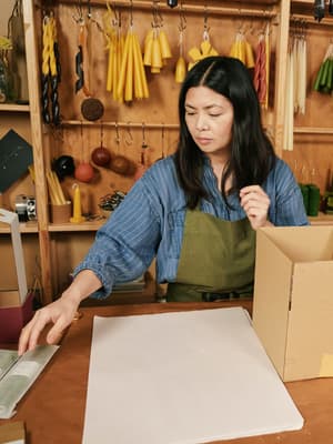 Ladeninhaber:in beim Vorbereiten eines Artikels zum Einwickeln und Verpacken für den Versand