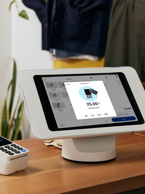 En POS-terminal og kortlæser står på en disk hos en lille til mellemstor virksomhed og viser en dialog om at betale kontaktløst eller indsætte kort