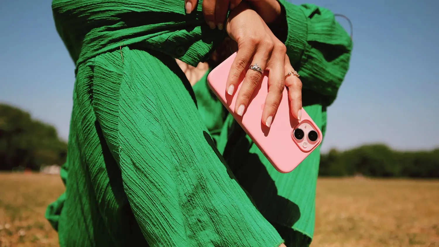 Mujer con un vestido verde sosteniendo un teléfono rosa