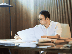 机に座って書類を確認している若いビジネスマン