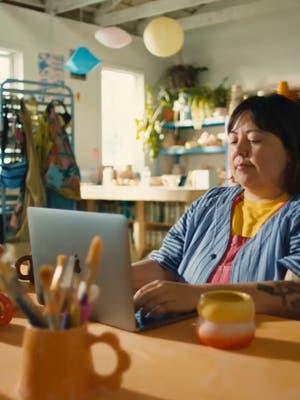 En kvindelig virksomhedsejer arbejder på en bærbar computer i sin butik.