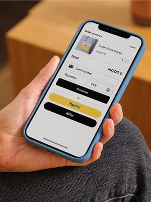 Person holder en mobiltelefon, der viser betalingsskærmen med betalingsmuligheder, herunder betalingskort, PayPal og Apple Pay.
