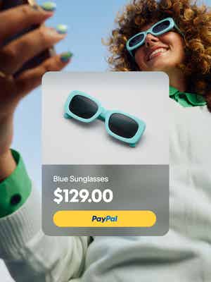Person utanför leende medan du tittar på telefonen och bär solglasögon med överlagring av blå solglasögon för $ 129 och PayPal knapp