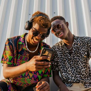 Friends smiling outside and looking at a phone together