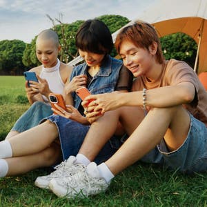 Friends smiling outside and looking at a phone together