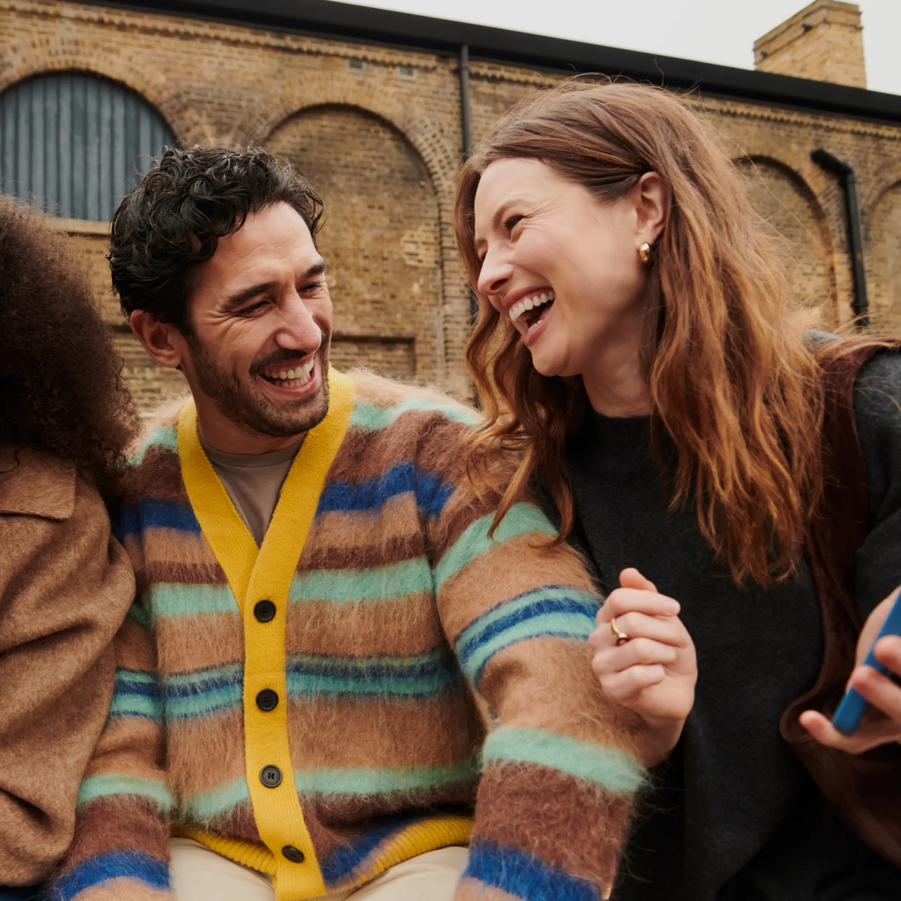 Friends smiling outside and looking at a phone together