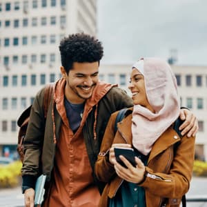 Friends smiling outside and looking at their phones