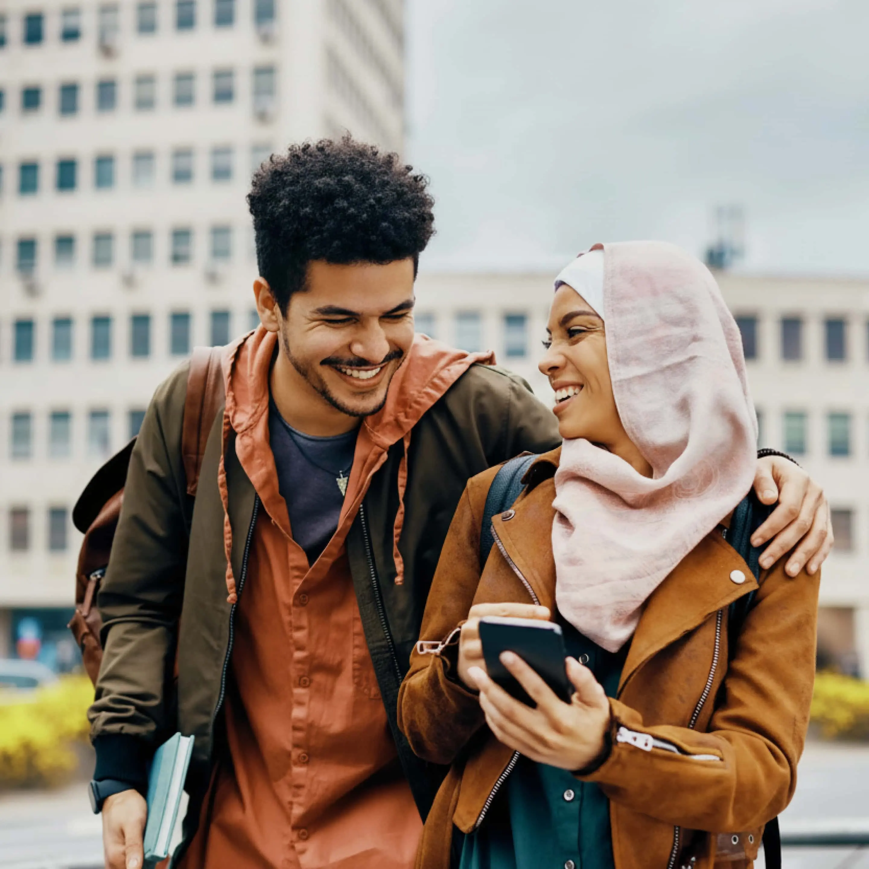 Friends smiling outside and looking at their phones