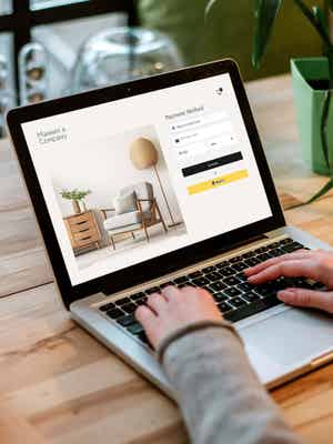 Person working on laptop computer with UI of PayPal checkout