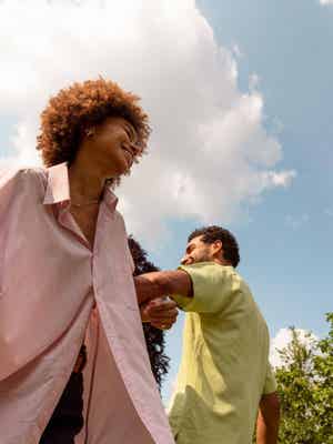 Man and woman interlocking arms, smiling outside
