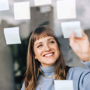 A man looking at some post its glued to a glass in front of him.