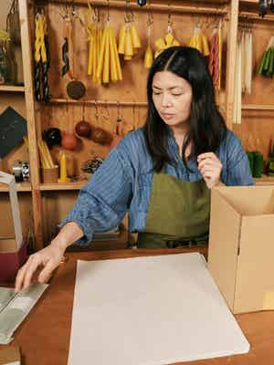 A shop owner preparing to wrap and box an item for shipping