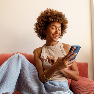 Woman with afro looking at her phone and smiling