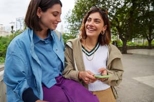 A woman holding her phone as she smiles at her friend