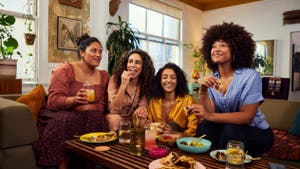 4 friends talking happily over a meal, showing an example of people who trust PayPal to send, spend, and manage their money