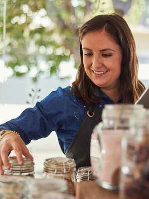 Smiling business owner checking her tea inventory in large glass mason jars