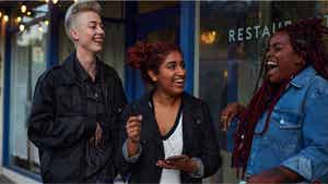 Three friends leaving a bar/restaurant, laughing together.