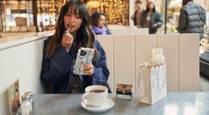 A person applying lipstick in a cafe.