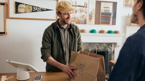 A merchant handing a customer their purchased items after using Zettle by PayPal POS solution to accept the payment.