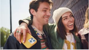 A woman holding a phone and smiling with her arm around a man.