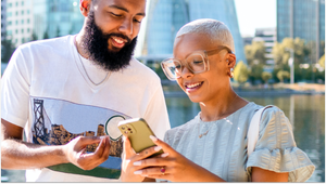 A woman showing a man what she’s doing on her phone.