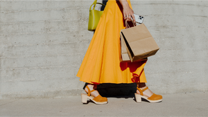 The bottom half of a woman walking outside after shopping.
